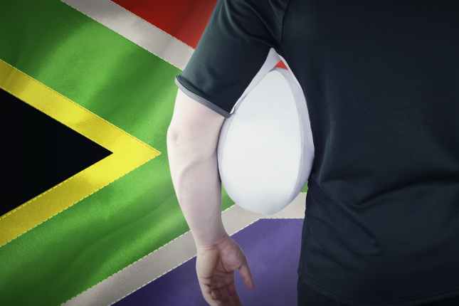 Rugby player holding a rugby ball by South Africa flag